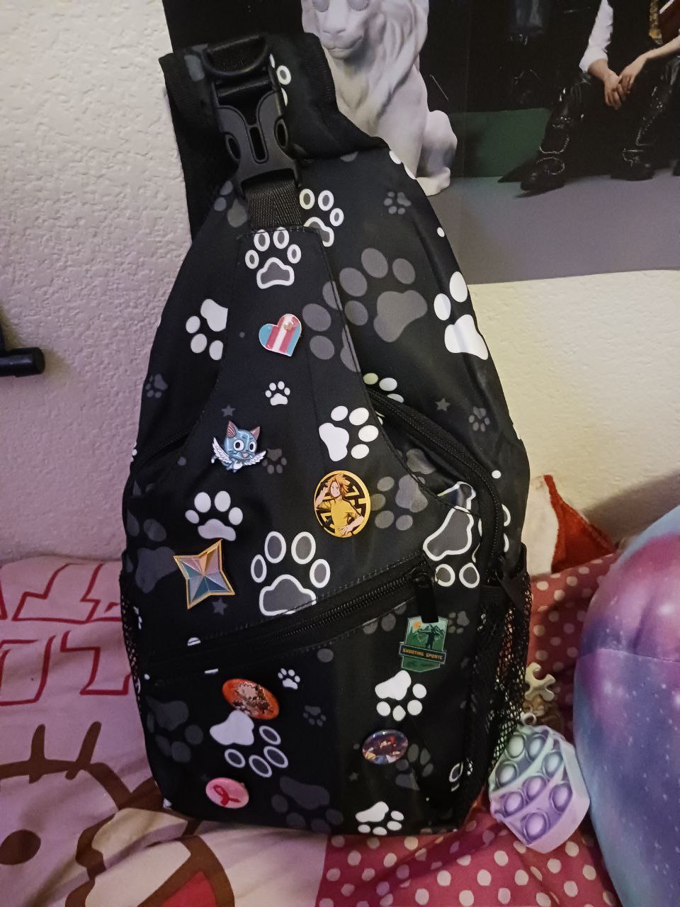 pawprint patterned sling bag with various pins on it